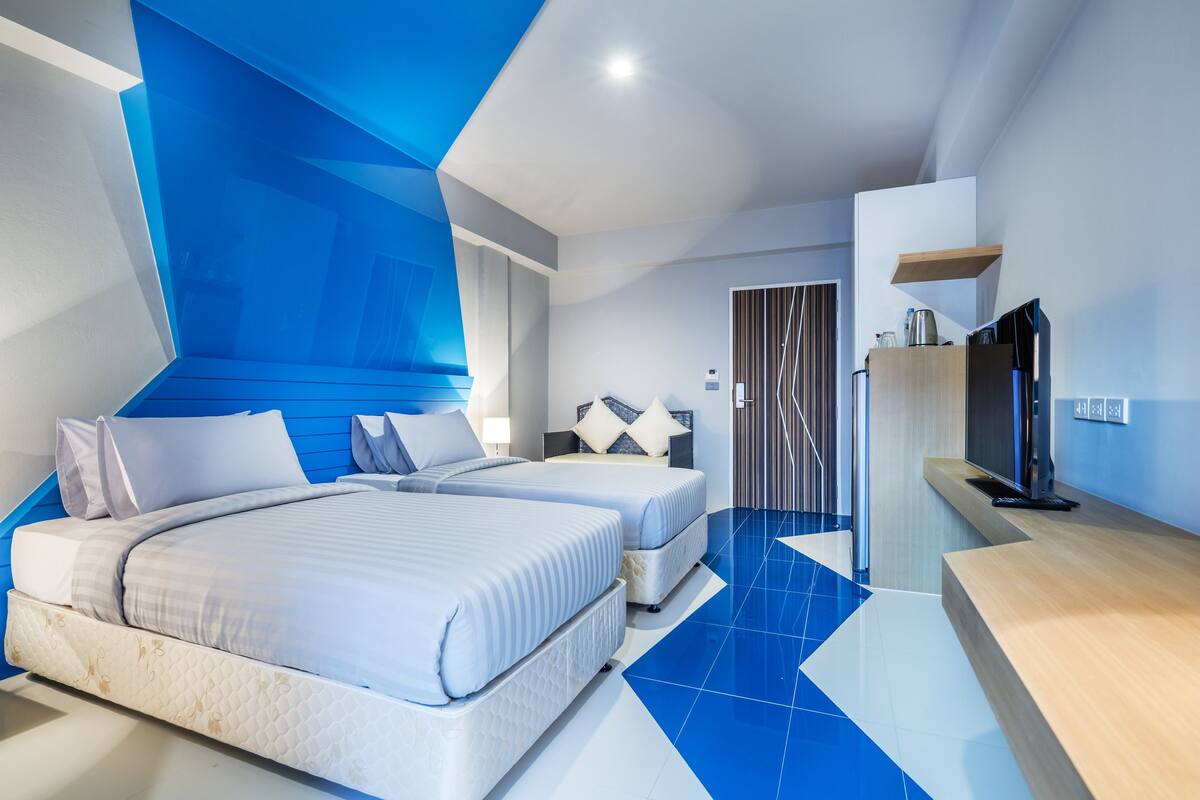 A modern hotel room with two beds, a TV, and a wooden cabinet.