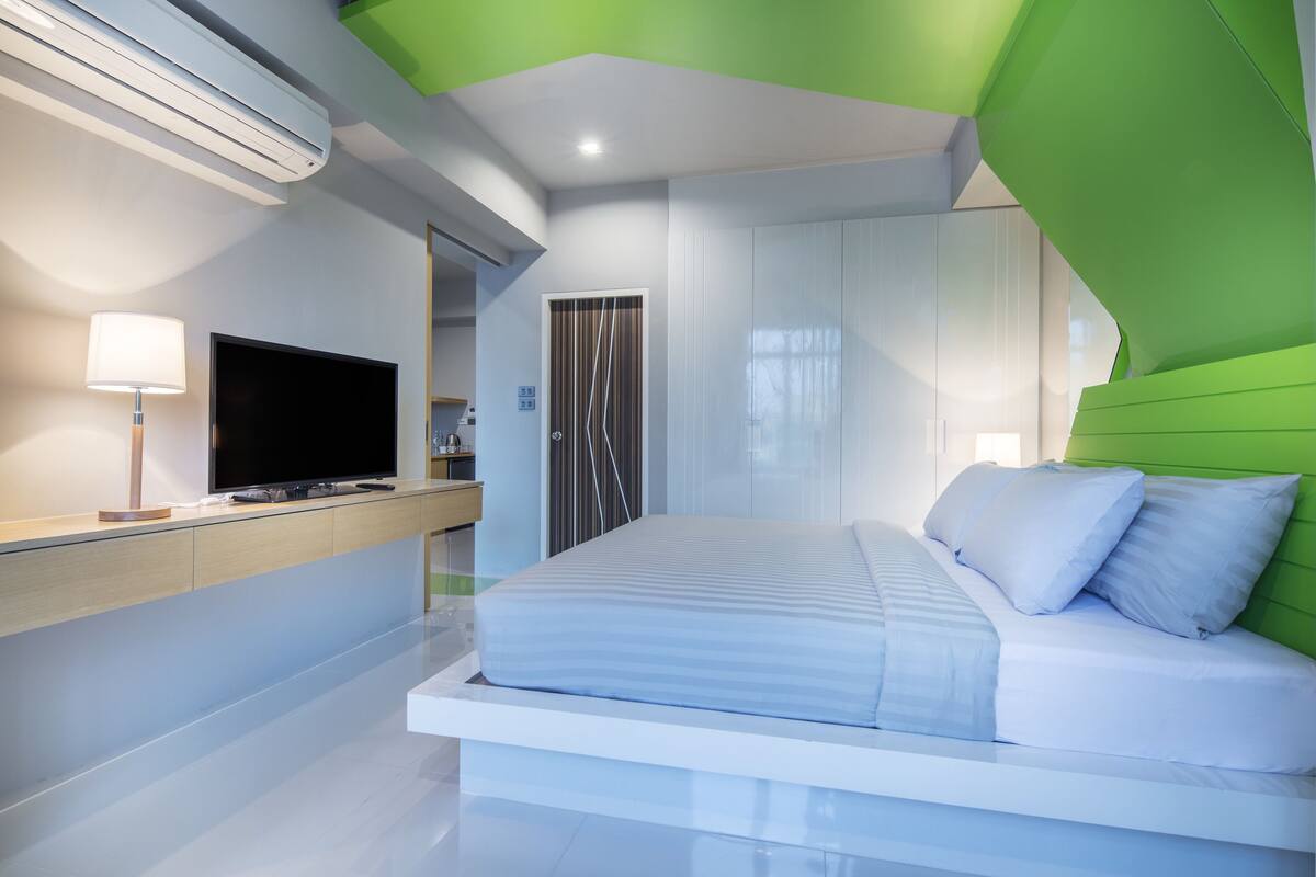 A modern bedroom with a bed, a TV, and a desk.