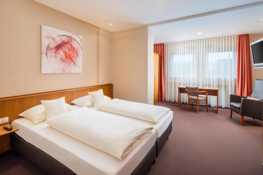 Habitación de hotel con dos camas, un escritorio, una silla, un televisor y un cuadro en la pared.
