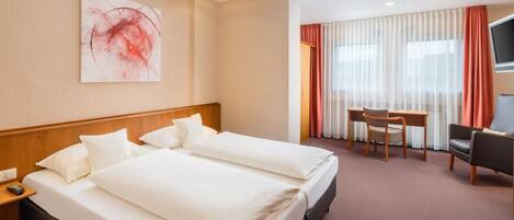 A hotel room with two beds, a desk, a chair, a TV, and a painting on the wall.