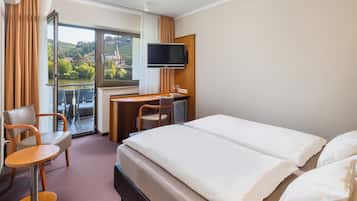 A hotel room with a bed, a desk, a chair, and a TV.