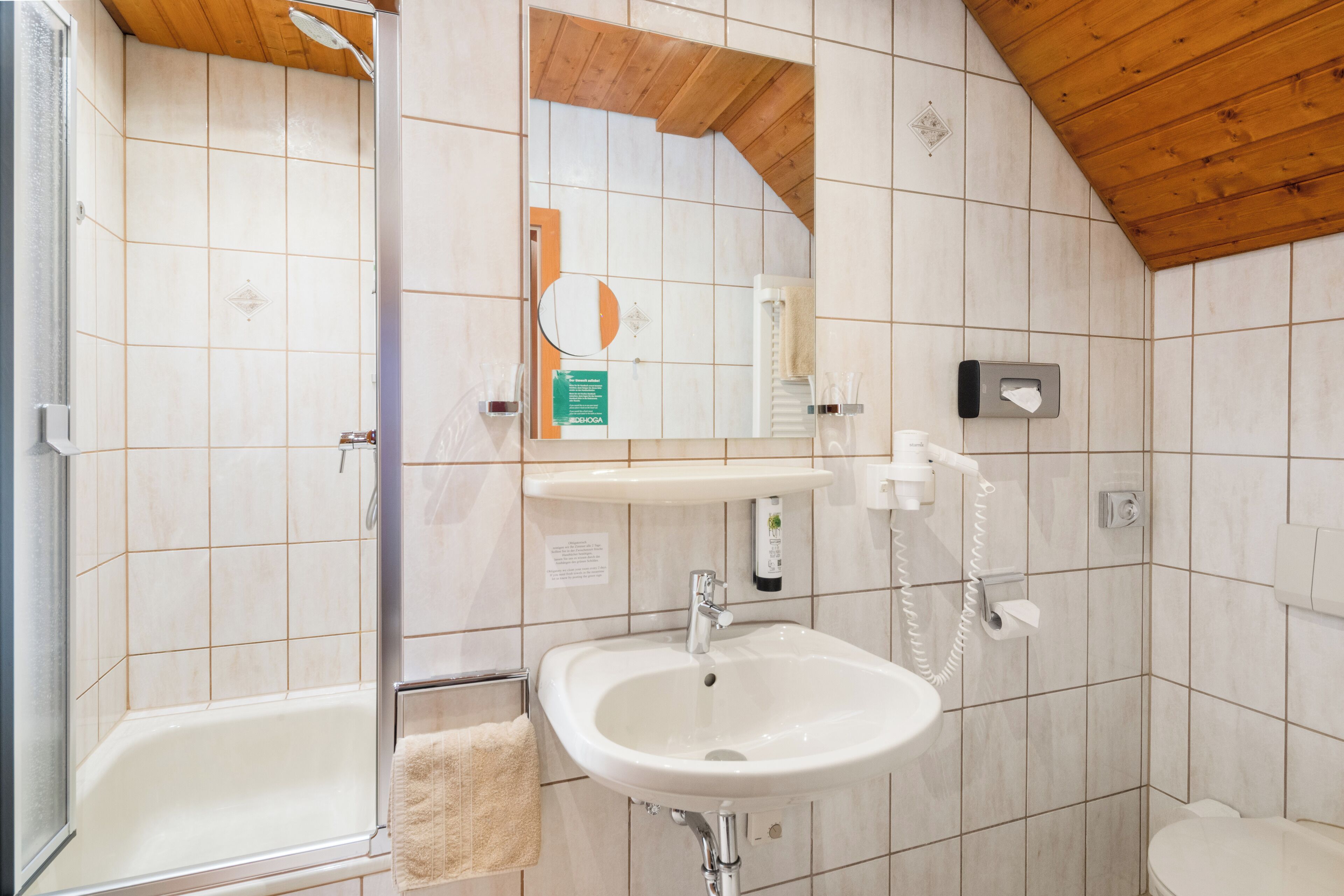 A bathroom with a bathtub, a sink, a mirror, and a towel rack.