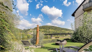 Un jardín con una silla, una mesa y vistas a un puente y colinas.