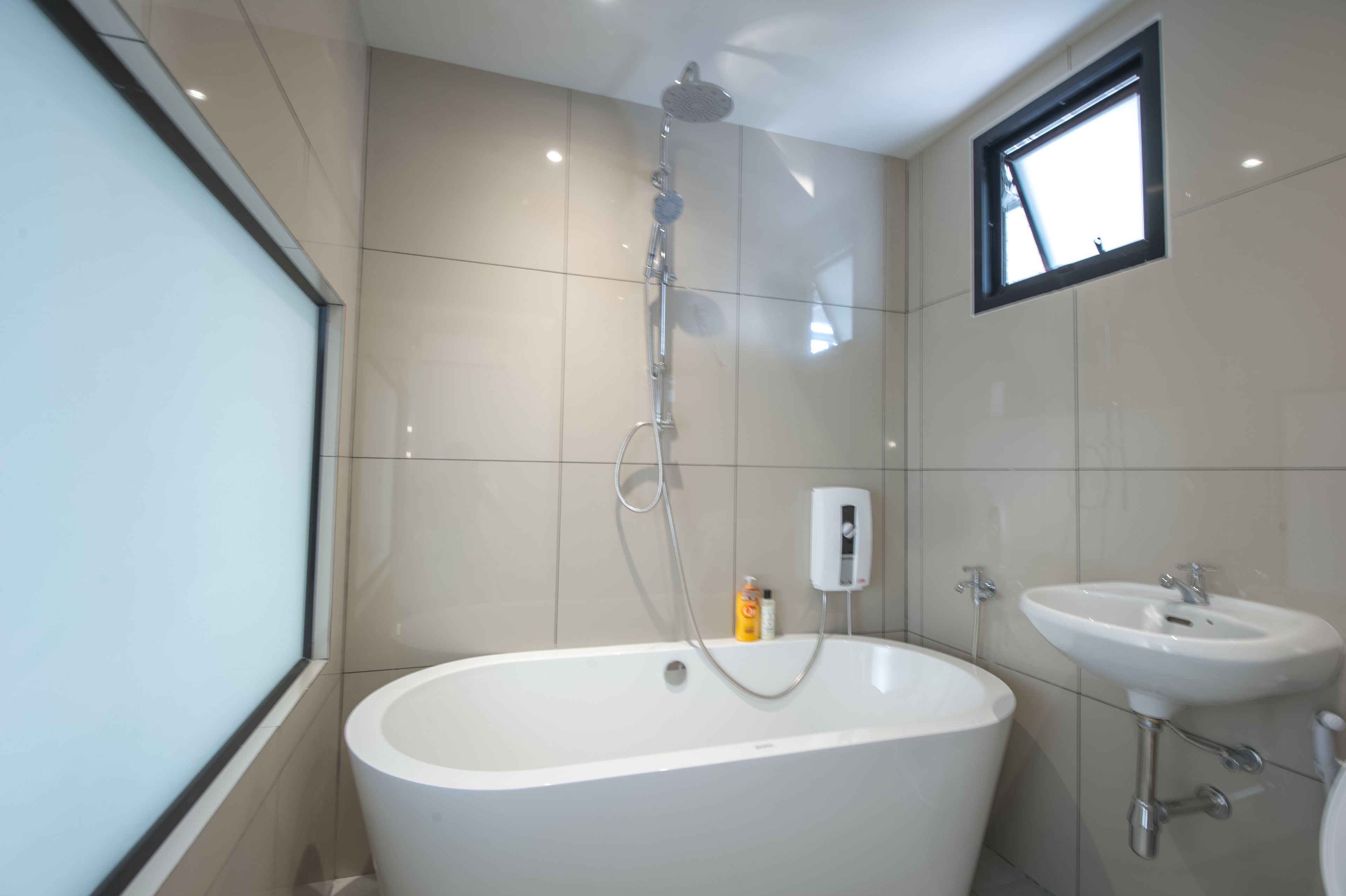A modern bathroom with a freestanding bathtub, a wall-mounted sink, and a window providing natural light.