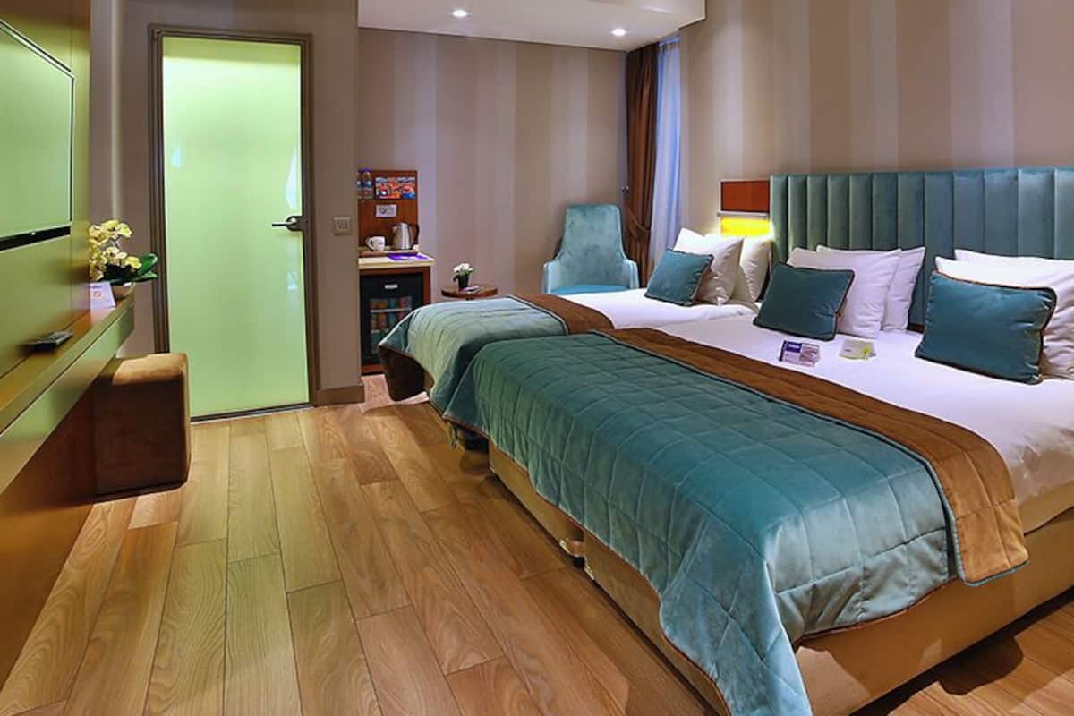 Een hotelkamer met een groot bed, nachtkastjes, een bureau en een stoel.
