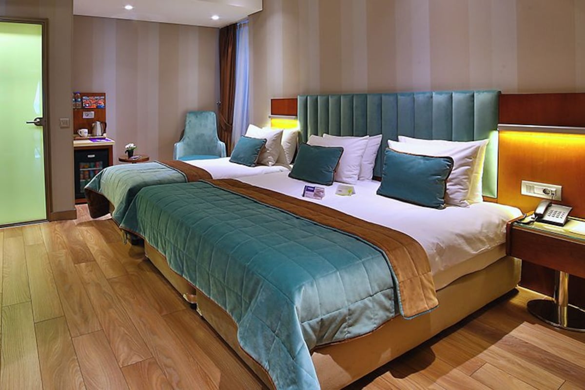 A hotel room with a large bed, bedside tables, a desk, and a chair.