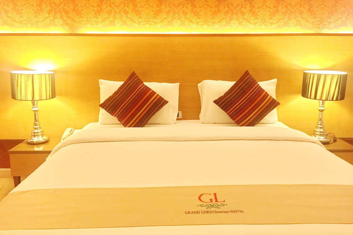 A hotel room with a bed, two nightstands, two lamps, and two pillows.