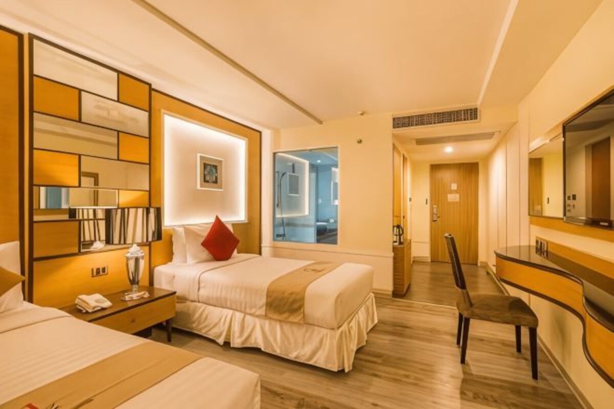 A hotel room with a large bed, bedside tables, a desk, and a mirror.