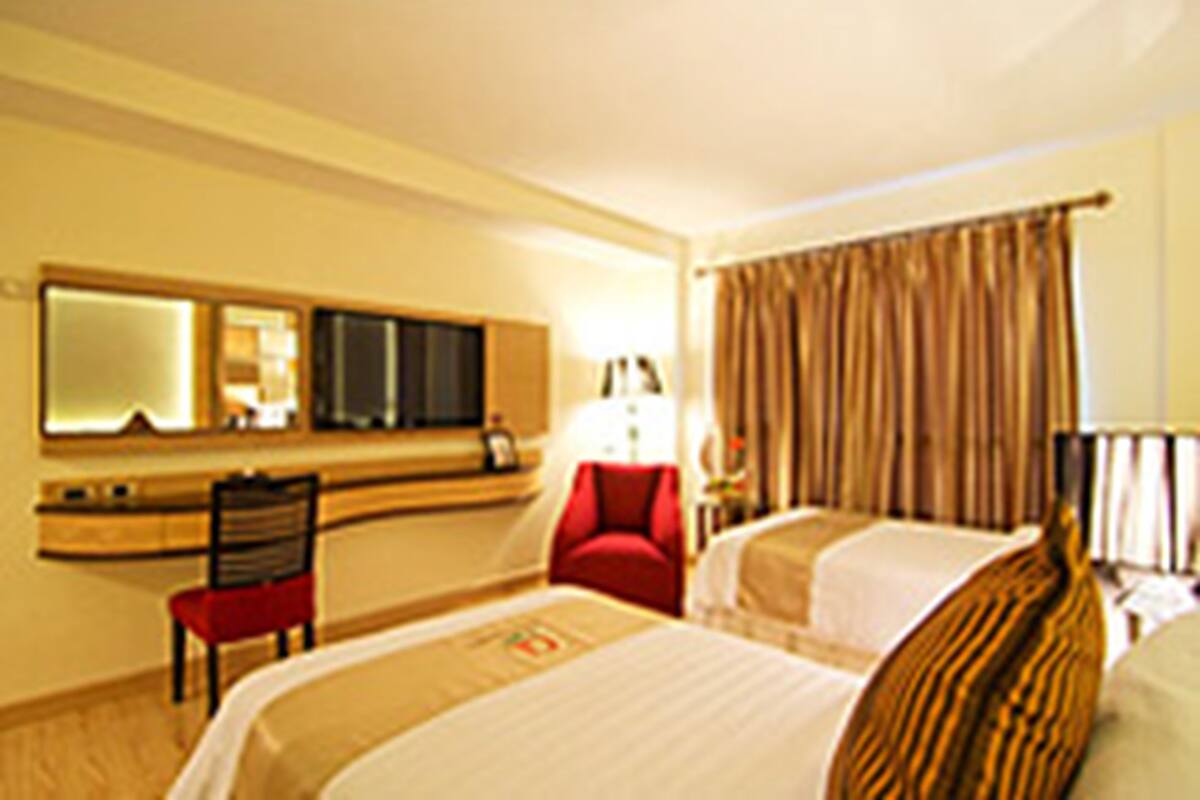 A hotel room with two beds, a desk, a chair, a TV, and a window with curtains.
