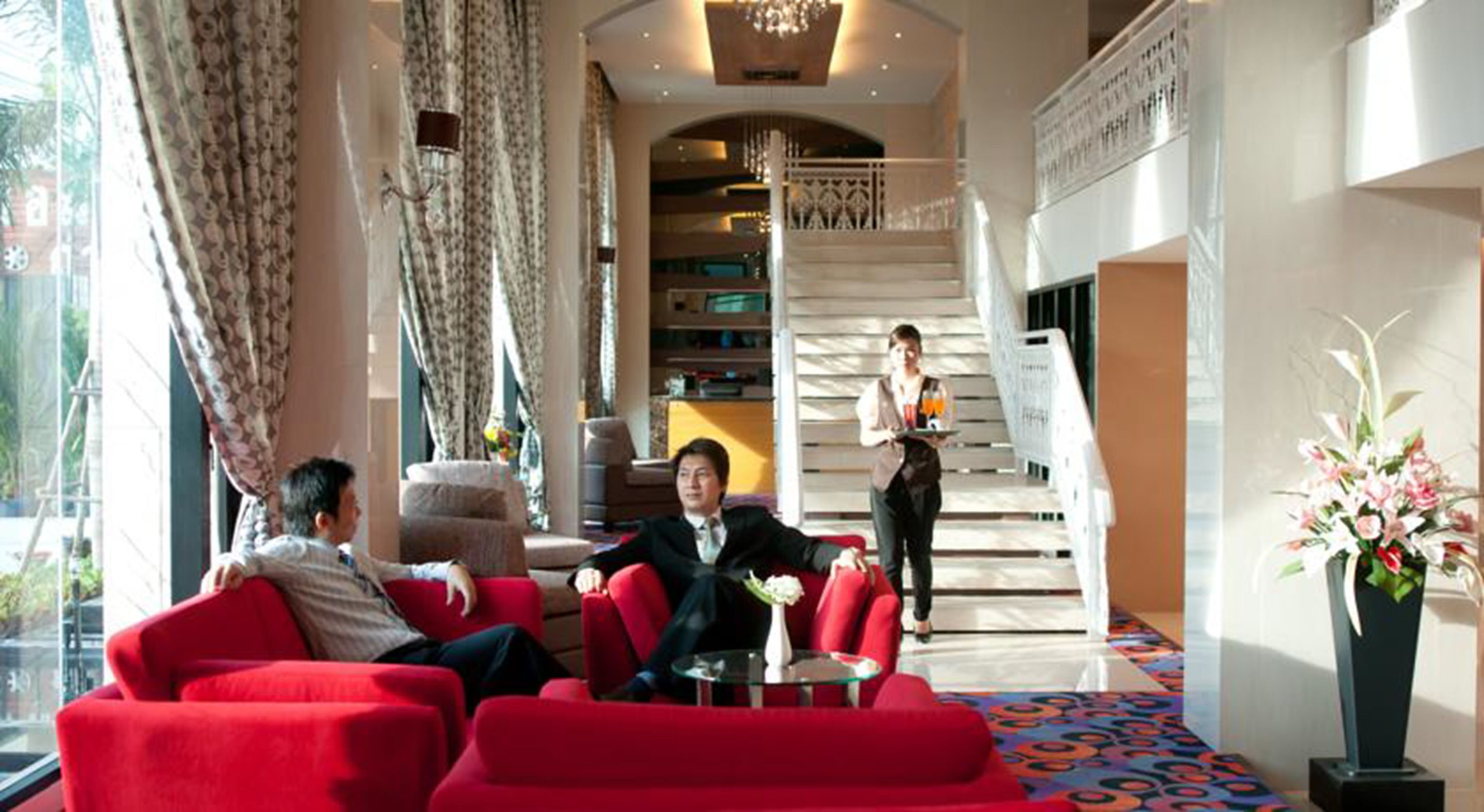 A hotel lobby with red seating, a staircase, and a reception area.