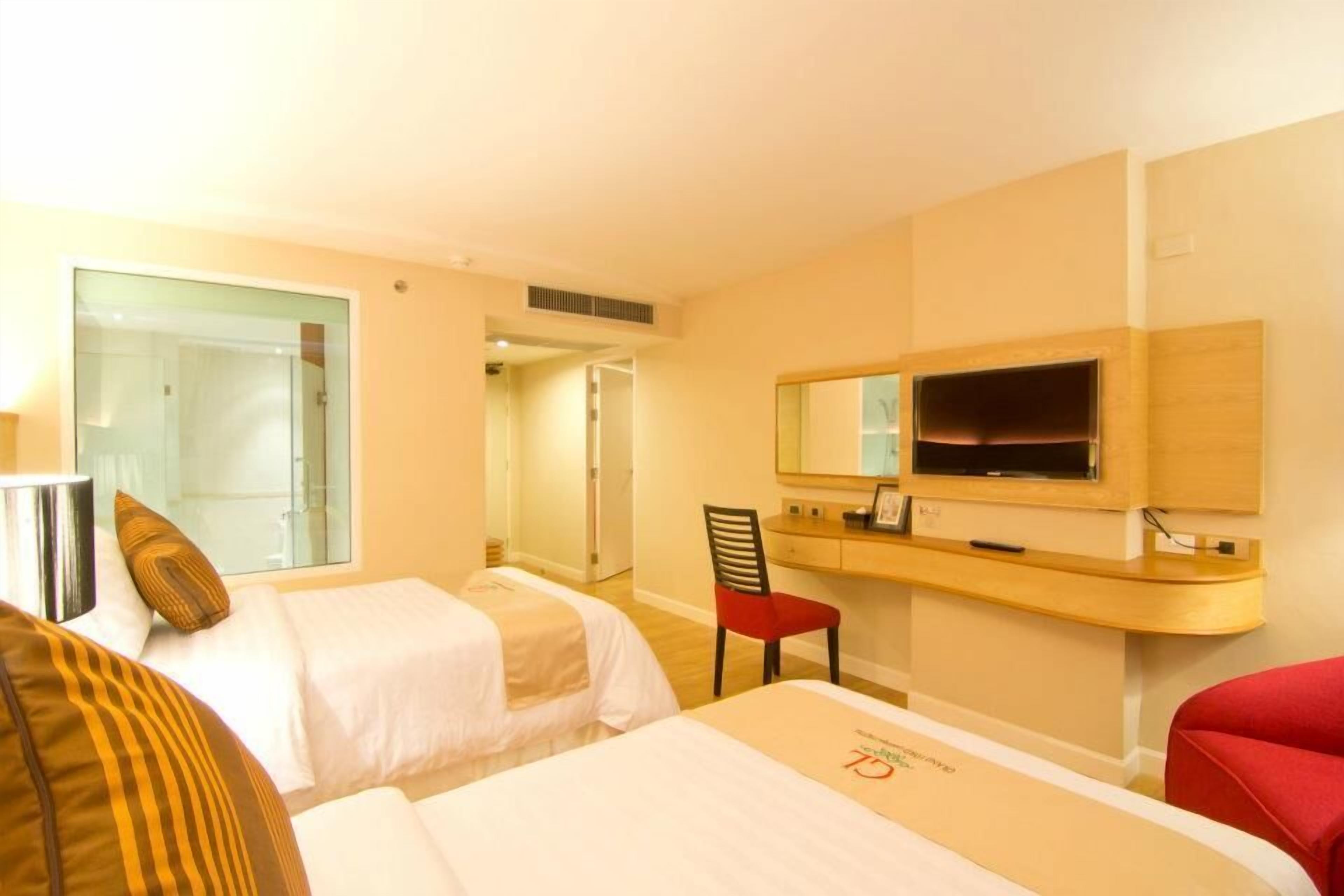 Habitación de hotel con dos camas, televisión, escritorio y una silla.
