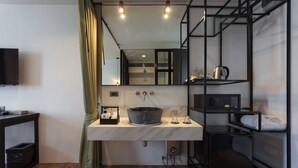 A modern bathroom with a marble sink, a large mirror, and a black shelving unit. - Oriental Heritage Hotel (Bangkok)