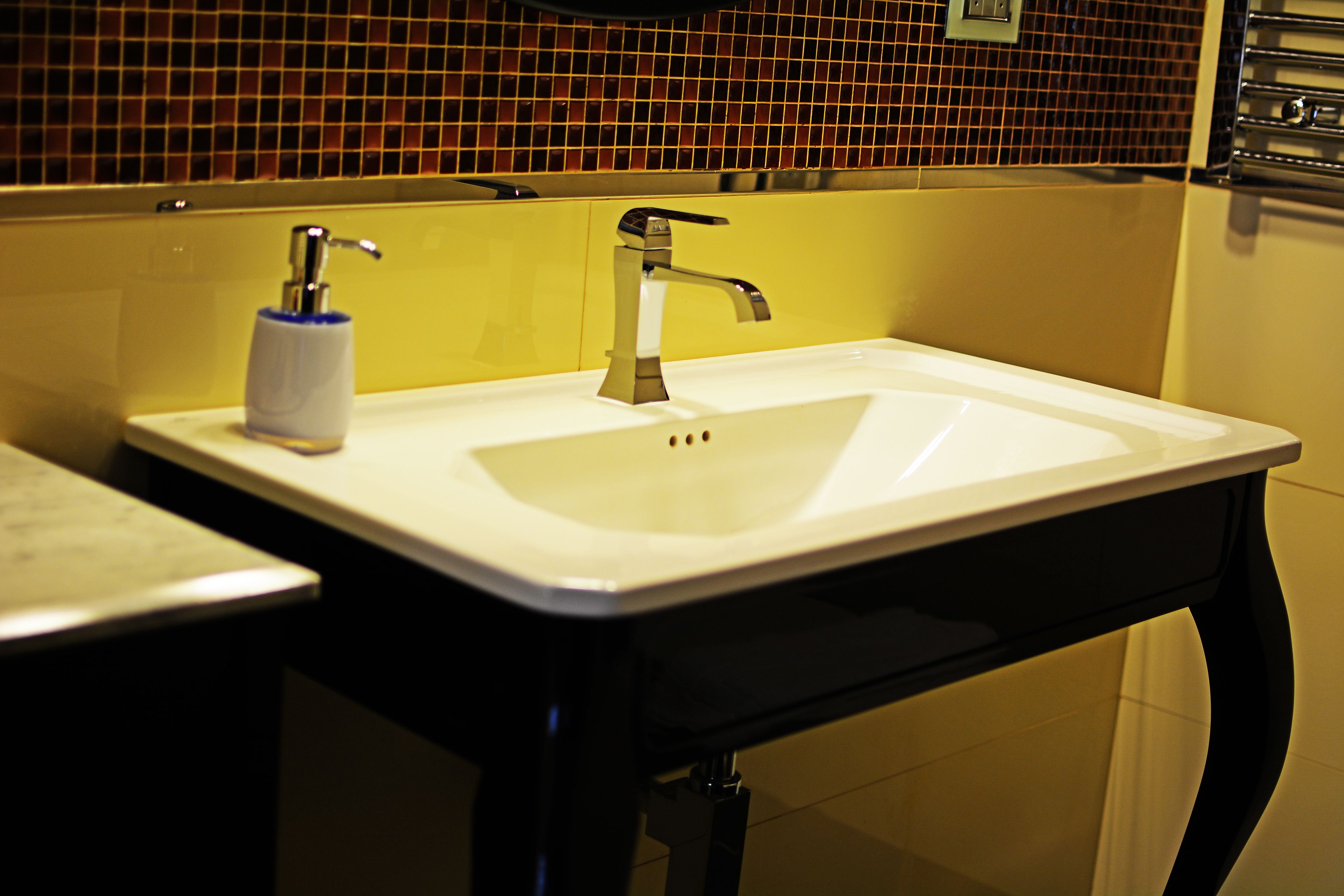 A bathroom with a white sink, a silver faucet, and a blue soap dispenser.