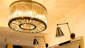 Un vestíbulo con candelabro, espejo, escalera y mostrador de recepción con plantas.