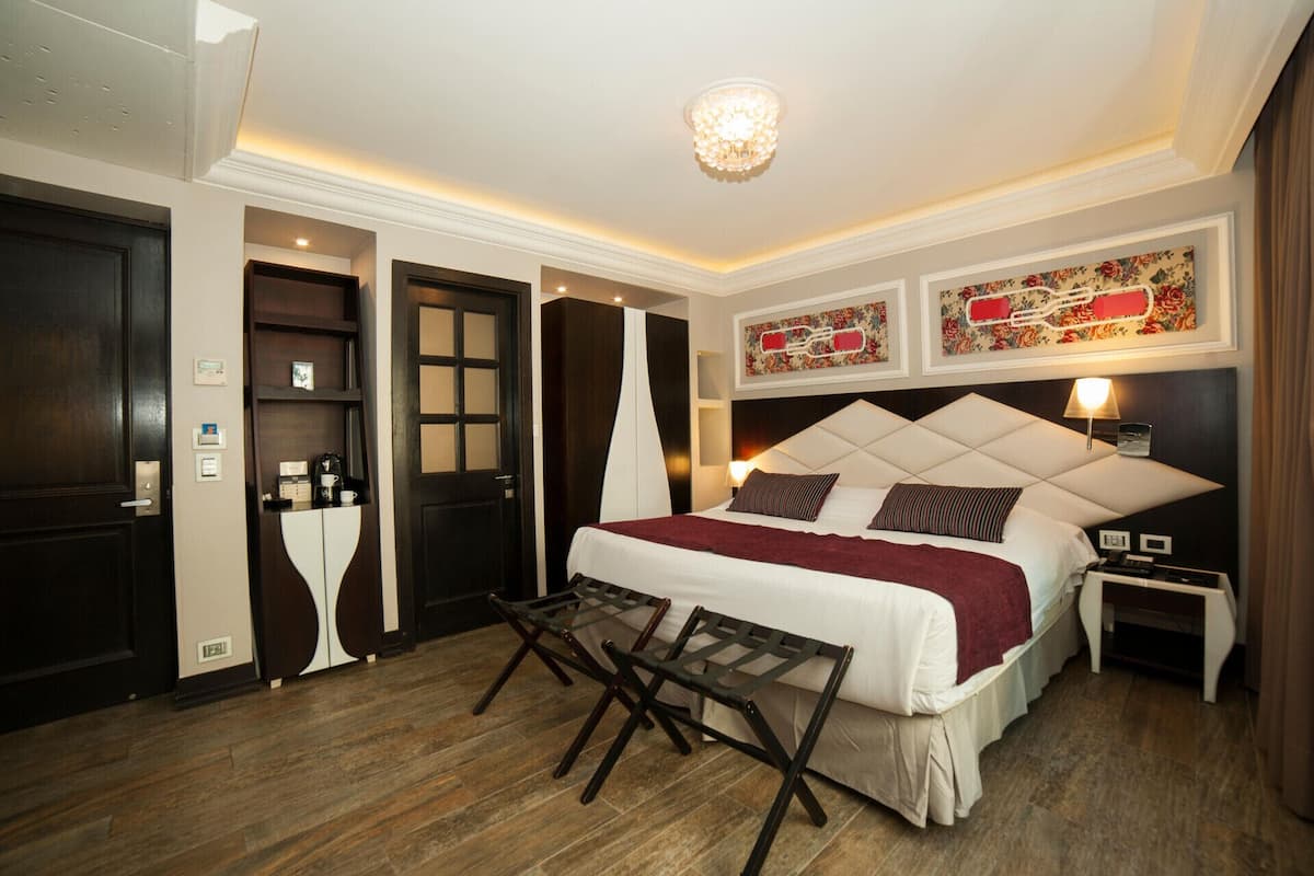 A hotel room with a bed, bedside table, lamp, and a small table with a chair.