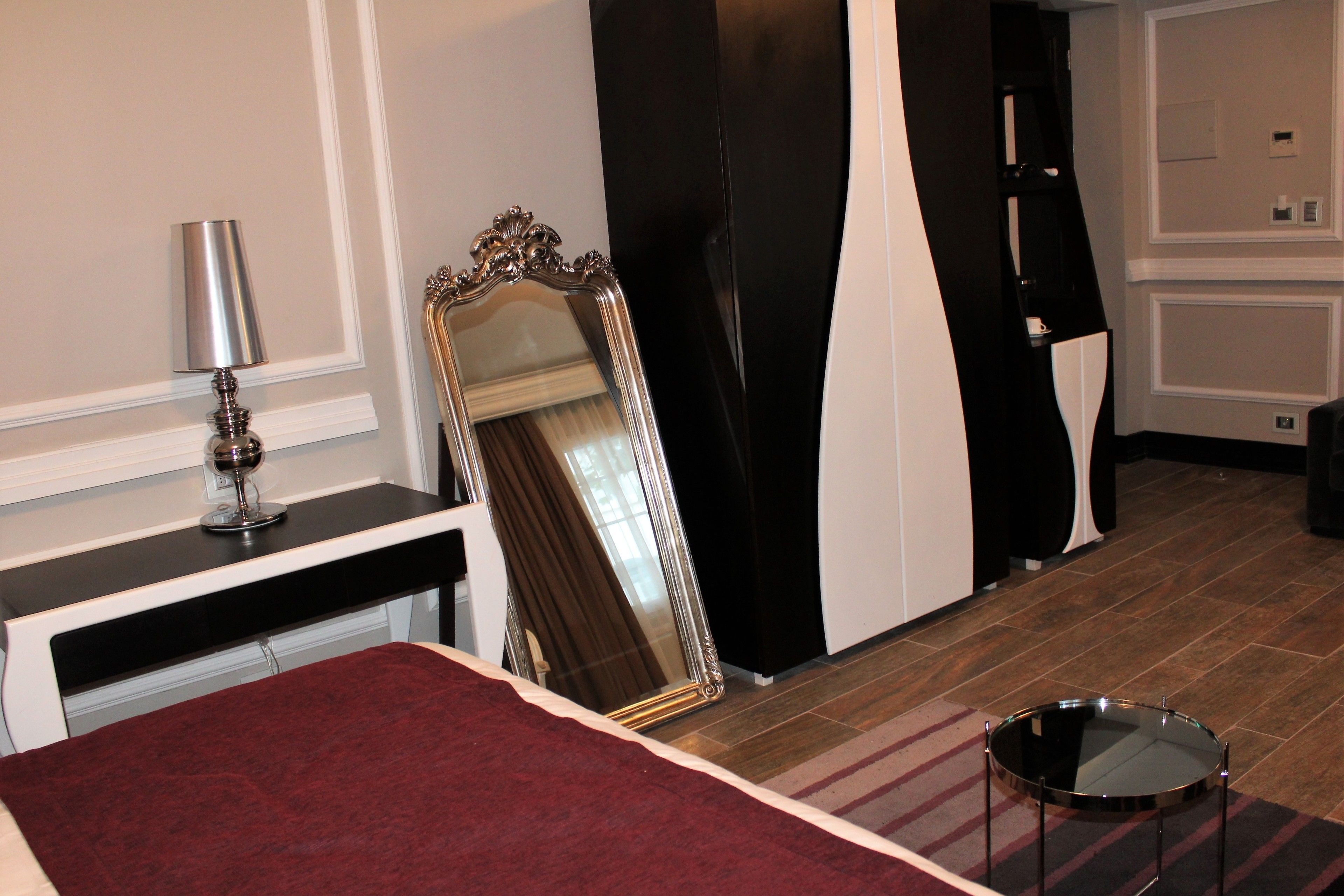 Une chambre d’hôtel avec un lit, un miroir, une lampe et une table ronde.