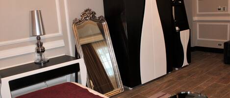 A hotel room with a bed, a mirror, a lamp, and a round table.
