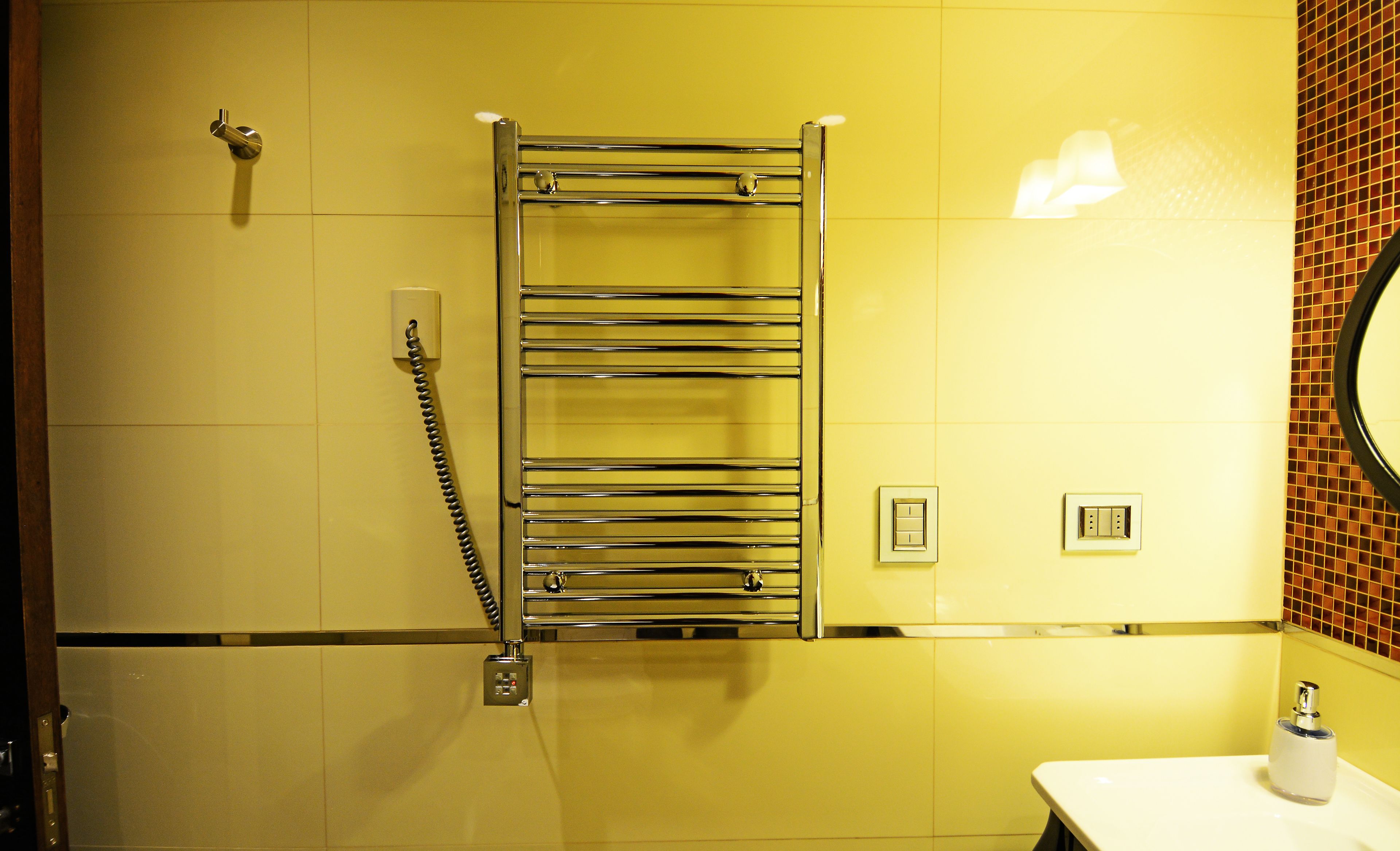 Un baño con un toallero de cromo, un lavabo blanco y un espejo.