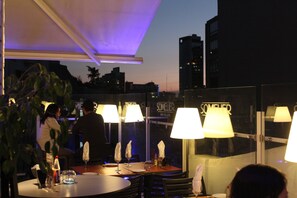 A rooftop bar with tables and chairs, illuminated by lamps. - Hotel Sommelier Boutique (Santiago)