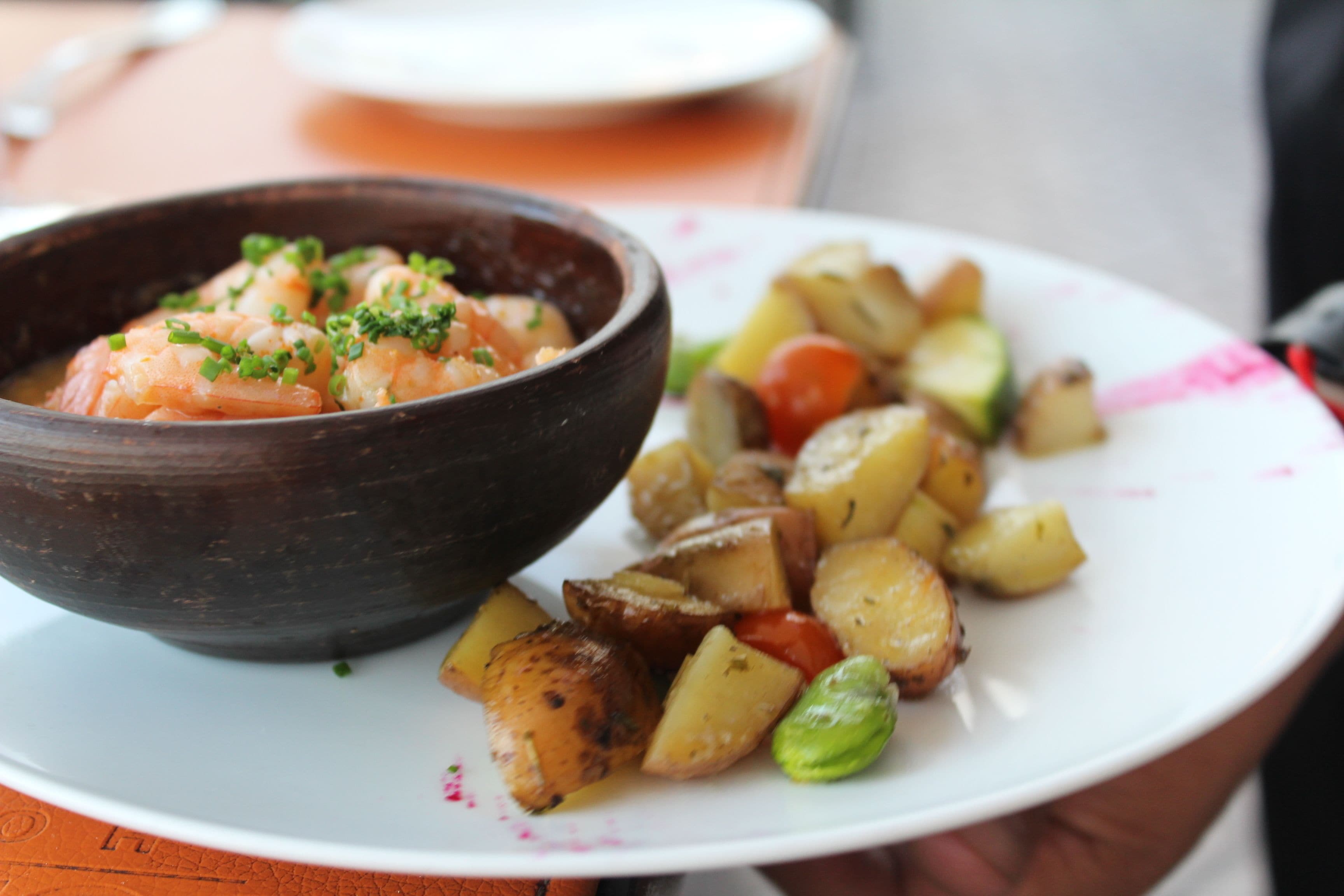 Un plato de papas asadas y un bol de ensalada de camarones.