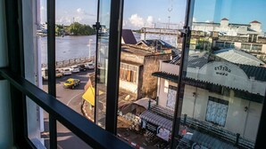 Uitzicht vanuit een raam op een straat met gebouwen, een waterpartij en een brug.
