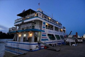 A multi-deck ferry with a name and logo on the side, docked at a pier. - The Port Hostel By Suwatchai (Surat Thani)