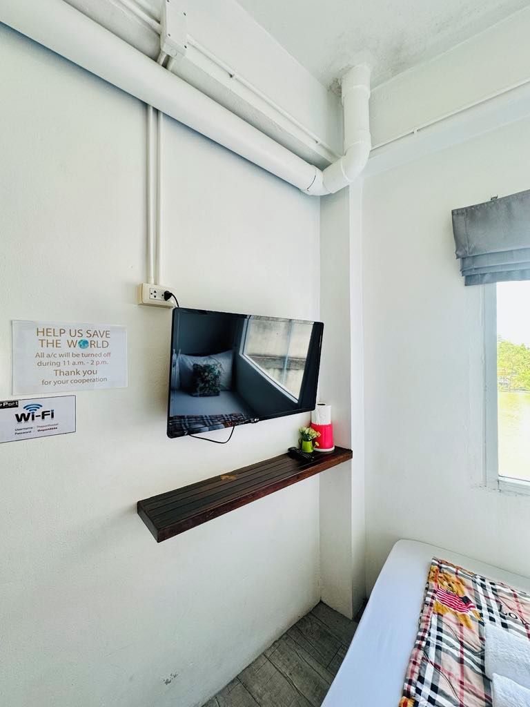 Ein Schlafzimmer mit an der Wand montiertem Fernseher, einem Wi-Fi-Symbol und einem Fenster mit Aussicht.
