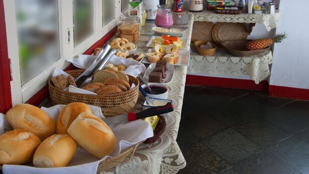 Un bufé de desayuno con pan, pasteles y bebidas sobre una mesa.