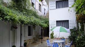 Un patio con una mesa y sillas, rodeado de muros blancos y follaje.