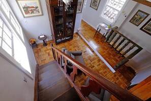 Una escalera de madera con barandilla, suelo de madera y vistas a un comedor con mesa y sillas.