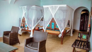 Ein Zimmer mit zwei Betten, jeweils mit Baldachin, und Korbmöbeln.