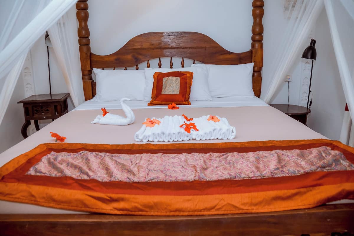 Un lit avec une tête de lit en bois, une literie blanche et des coussins décoratifs en forme de cygne.