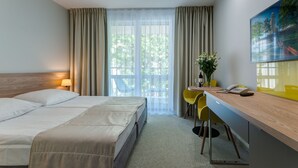 A hotel room with a bed, a desk with a chair, a phone, and a painting on the wall. - Osrodek Wypoczynkowy Zorza (Kolobrzeg)