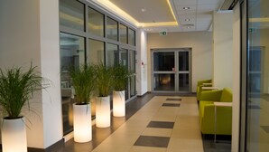 A modern lobby with glass doors, potted plants, and green seating. - Osrodek Wypoczynkowy Zorza (Kolobrzeg)