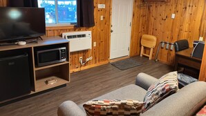 Une chambre confortable, aménagée dans le style d’un chalet, équipée d’une télévision, d’un climatiseur, d’un coin salon et d’une porte.