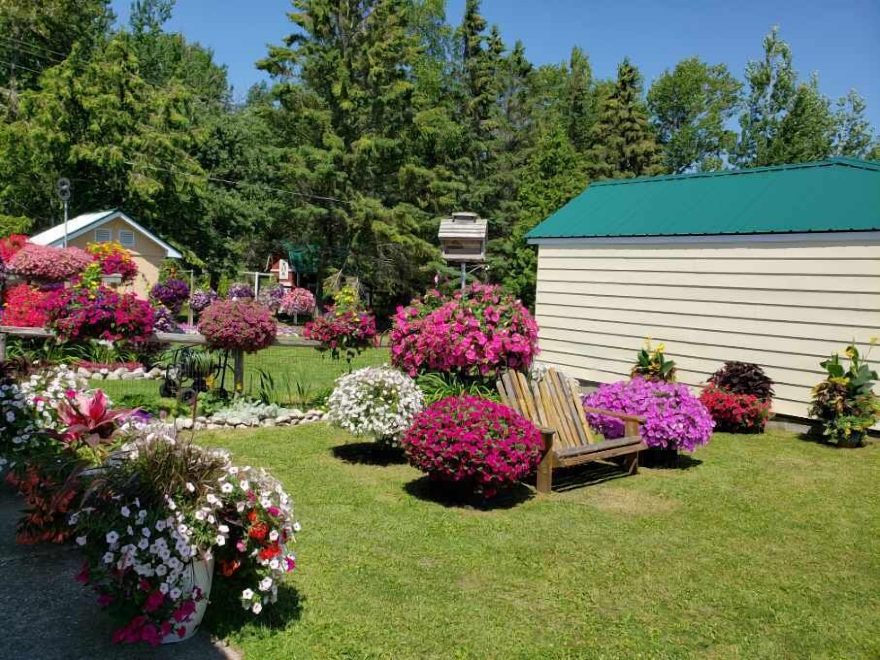 A garden with various flower beds and a wooden chair.
