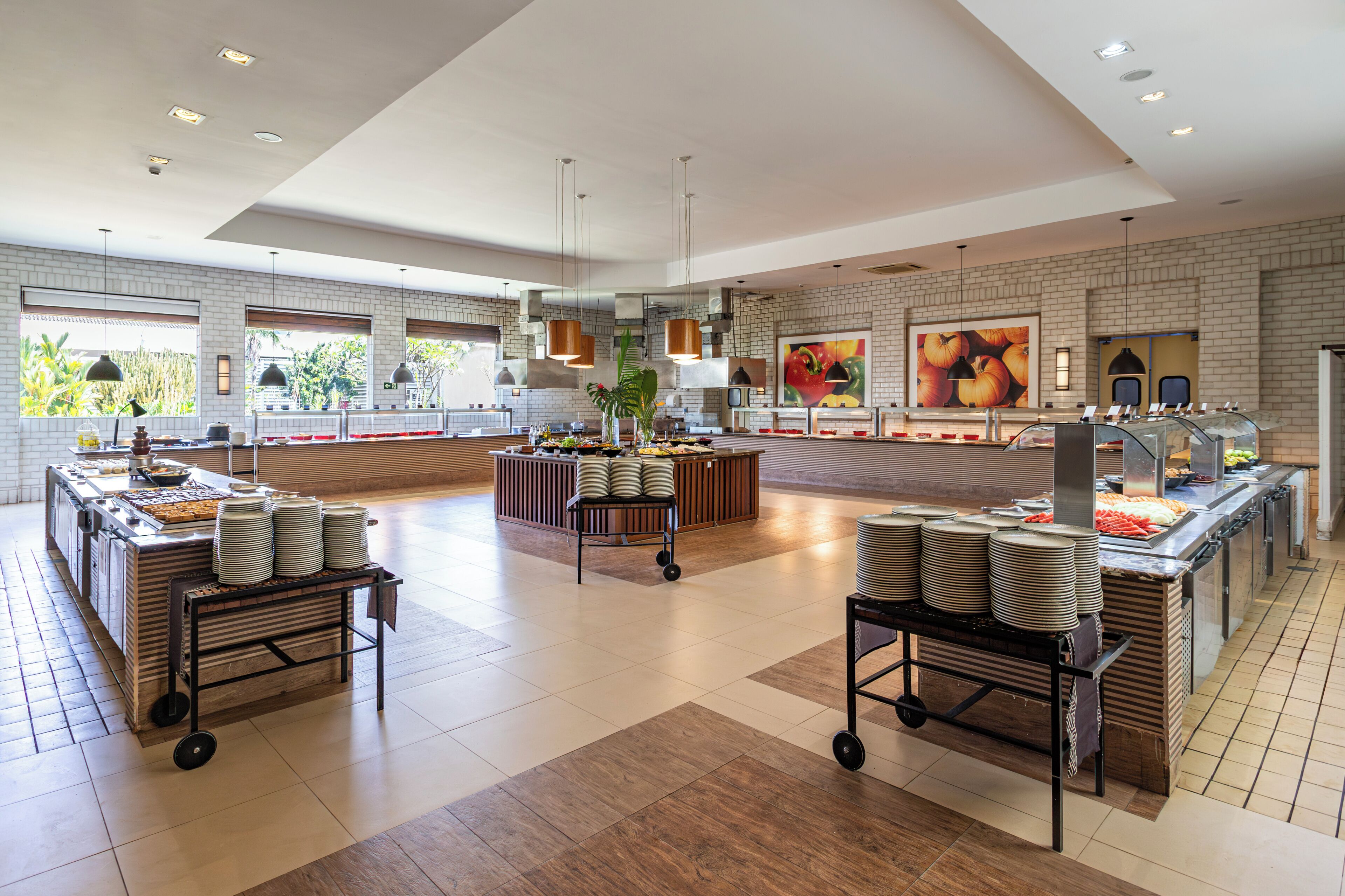 A spacious, modern kitchen area with multiple food stations, large windows, and a clean, tiled floor.