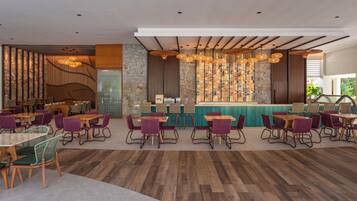 Un restaurante moderno con suelo de madera, sillas de mimbre y una zona de bar con un fondo de pared de piedra.