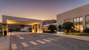 A modern resort entrance with a paved driveway, palm trees, and a sign for Rio Quente Cristal Resort. - Rio Quente Resorts - Cristal Resort (Rio Quente)