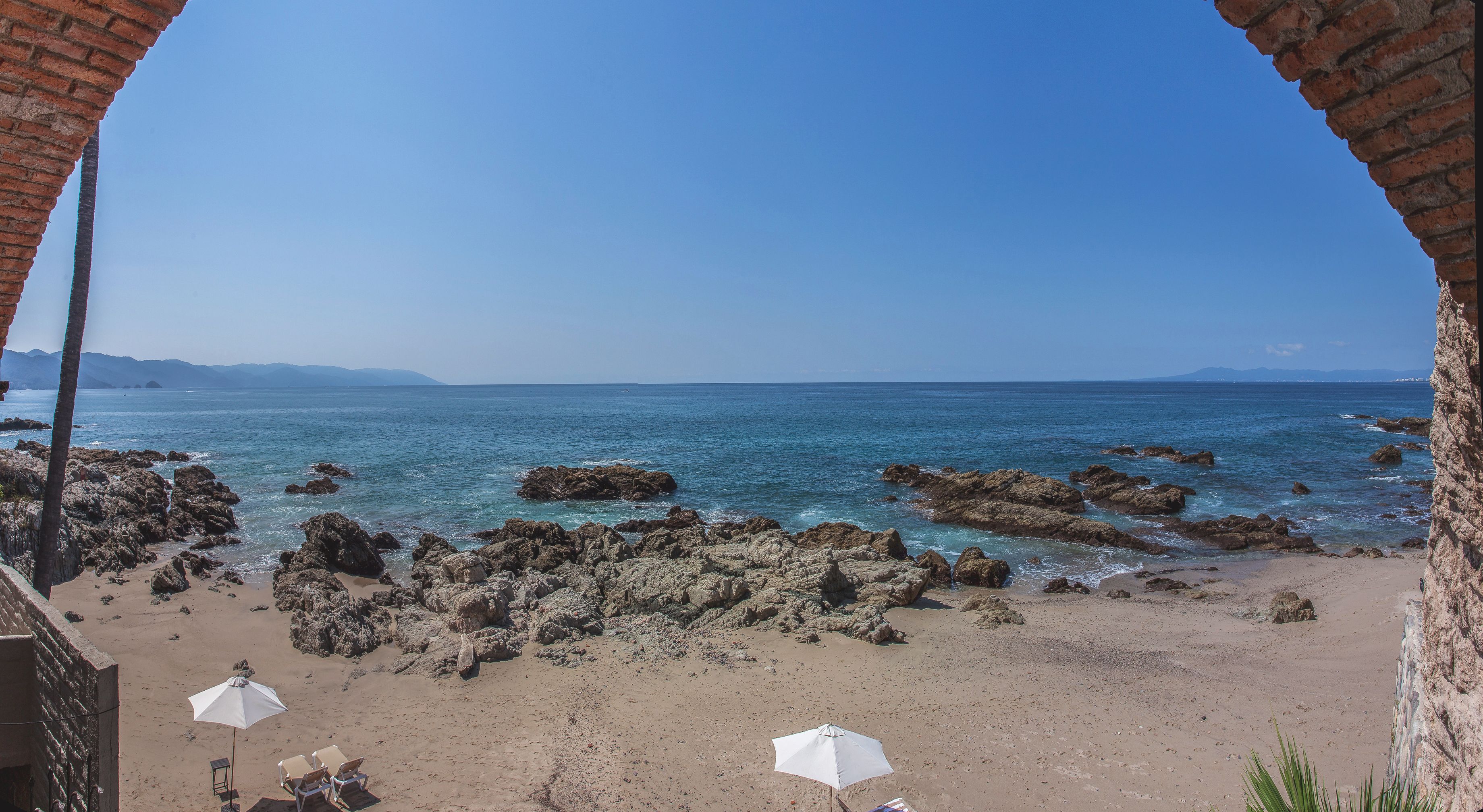 Une plage au paysage rocheux, bordée d’une eau d’un bleu limpide.