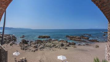 A beach with rocky terrain and clear blue water.