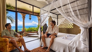 Ein Zimmer mit einem Bett, einer Bank und Meerblick.