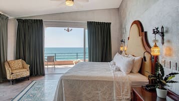 Habitación de hotel con cama, una silla, un escritorio, una lámpara y vista al océano.