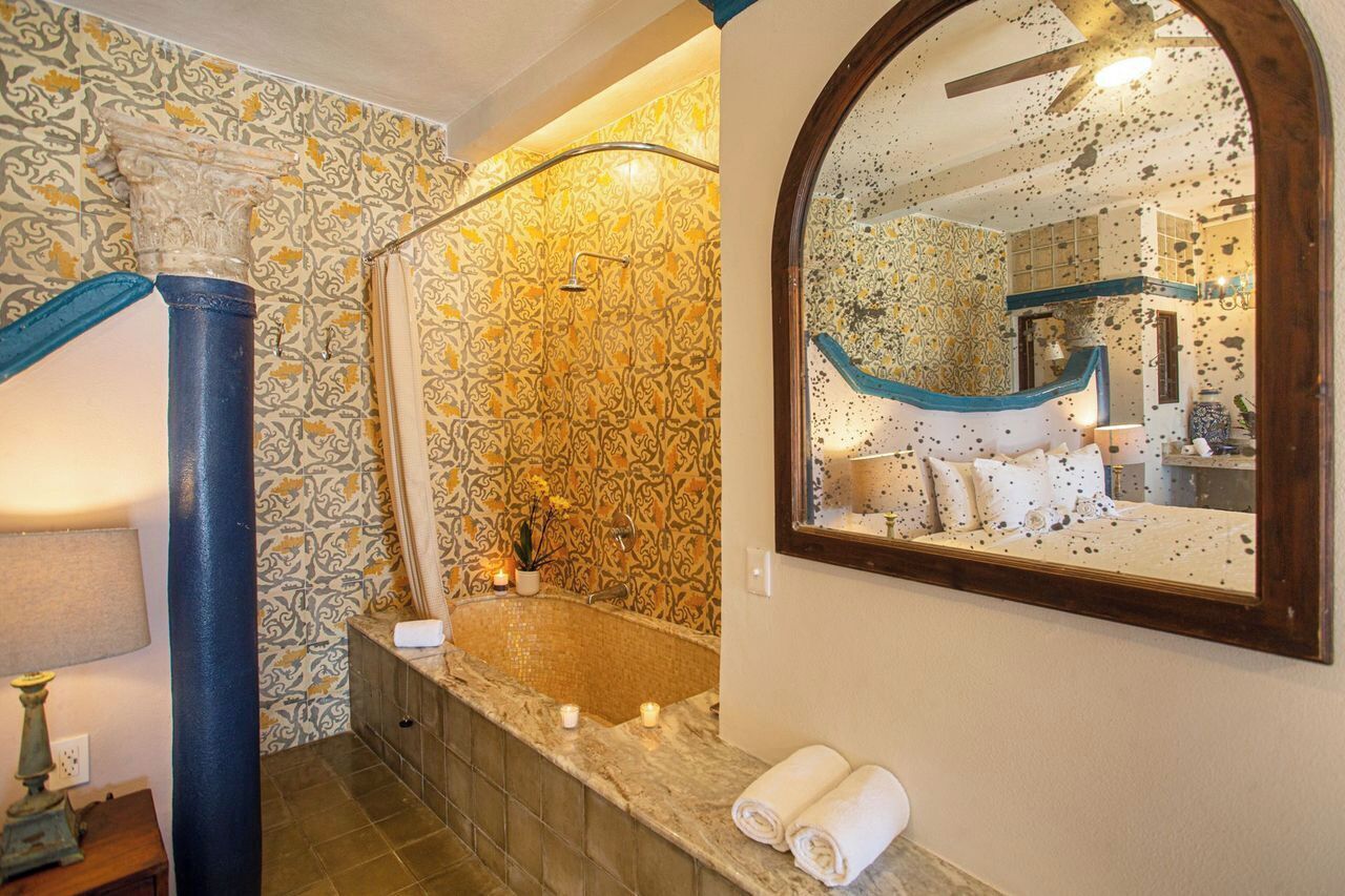 Un baño con bañera, espejo y paredes con diseño.