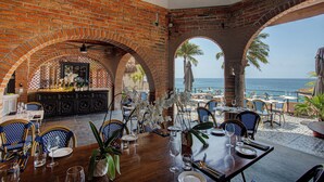 Een restaurant met bakstenen bogen, terras en uitzicht op zee.