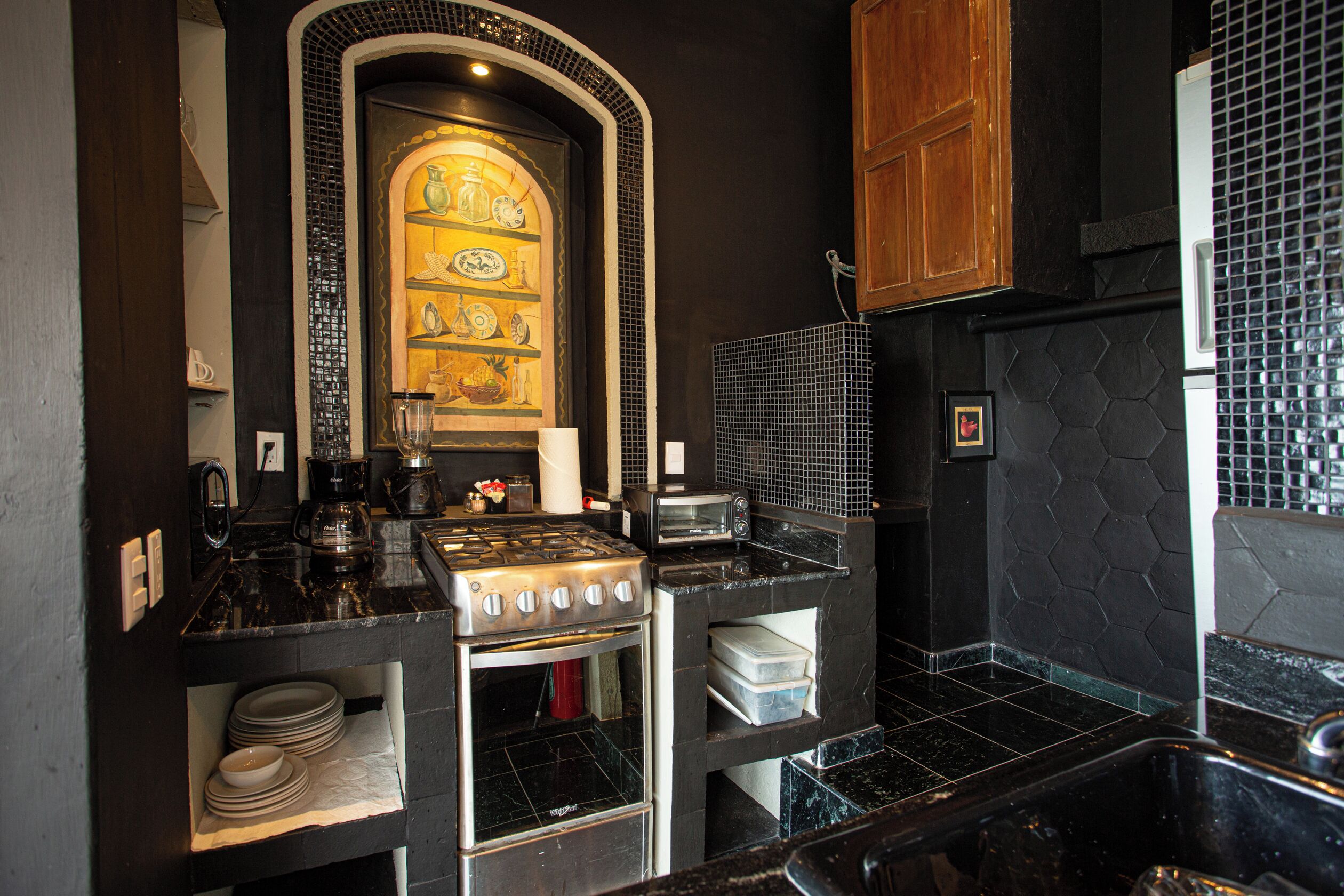 A kitchen with a stove, oven, and microwave. There are shelves with dishes and a coffee maker.
