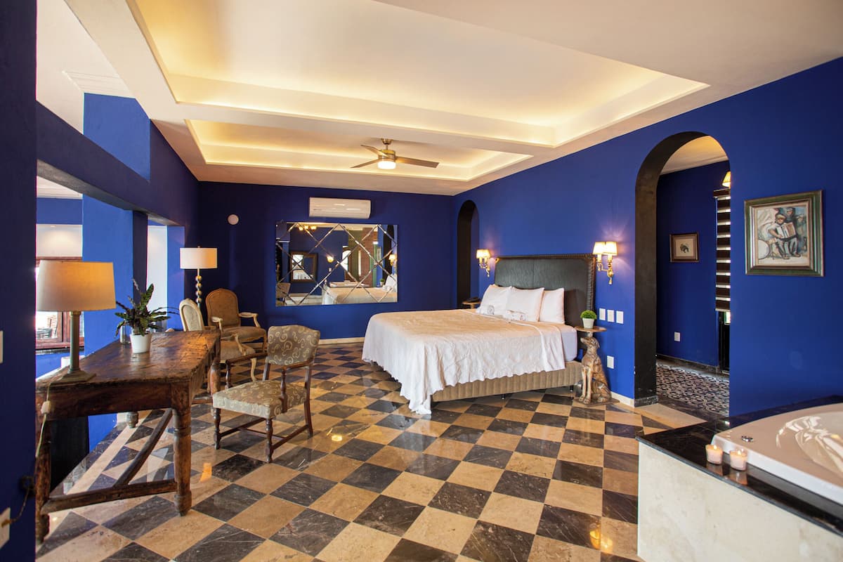 Ein Hotelzimmer mit Schachbrettmuster-Boden, einem Bett, einem Schreibtisch mit Lampe und einer Badewanne.