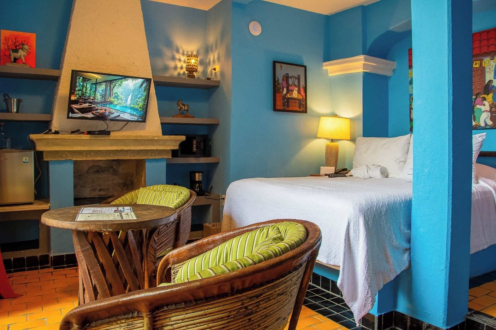 A hotel room with a bed, a television, a fireplace, and a chair.