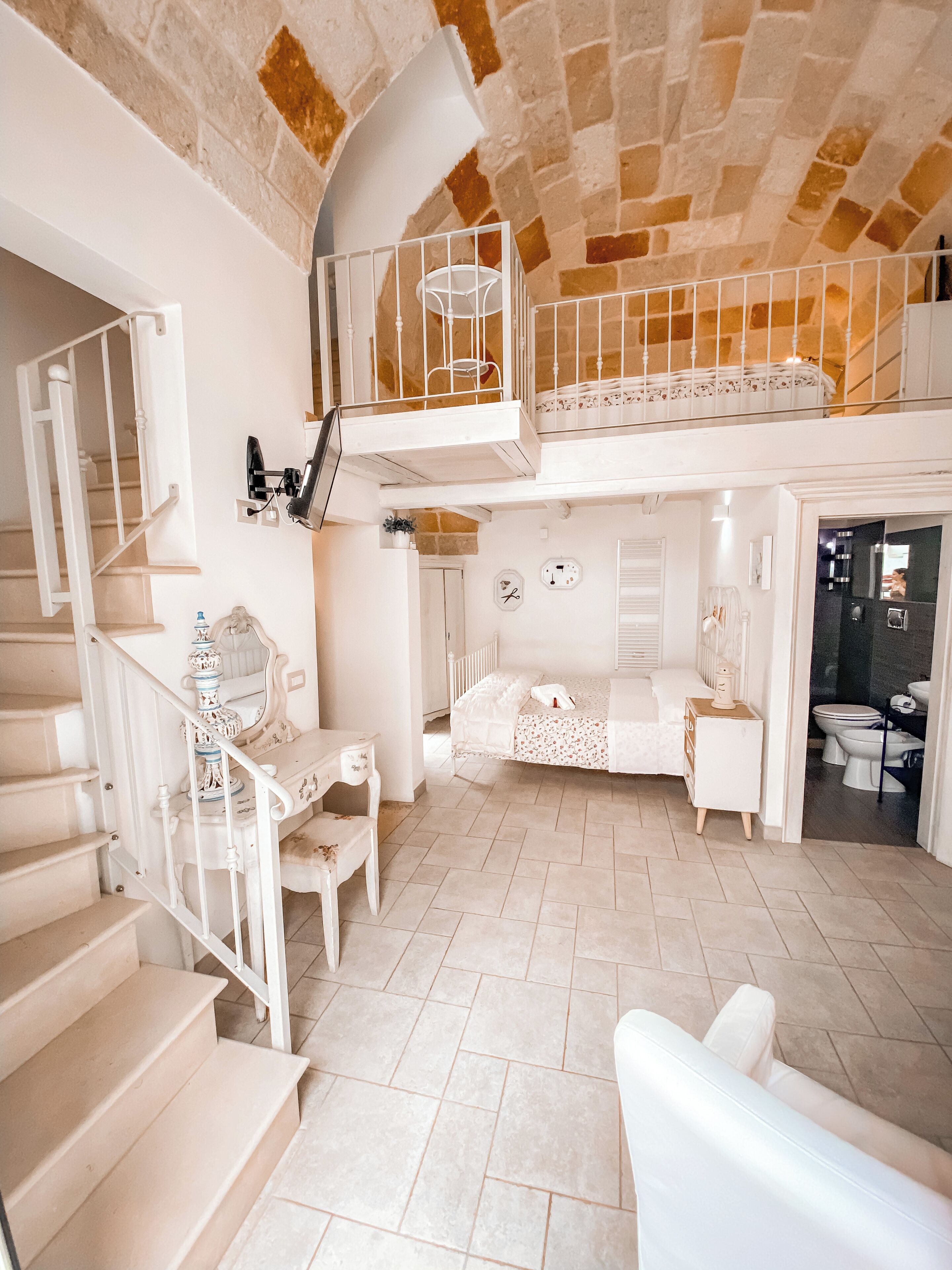 A spacious interior with a staircase, a balcony, and a bathroom.