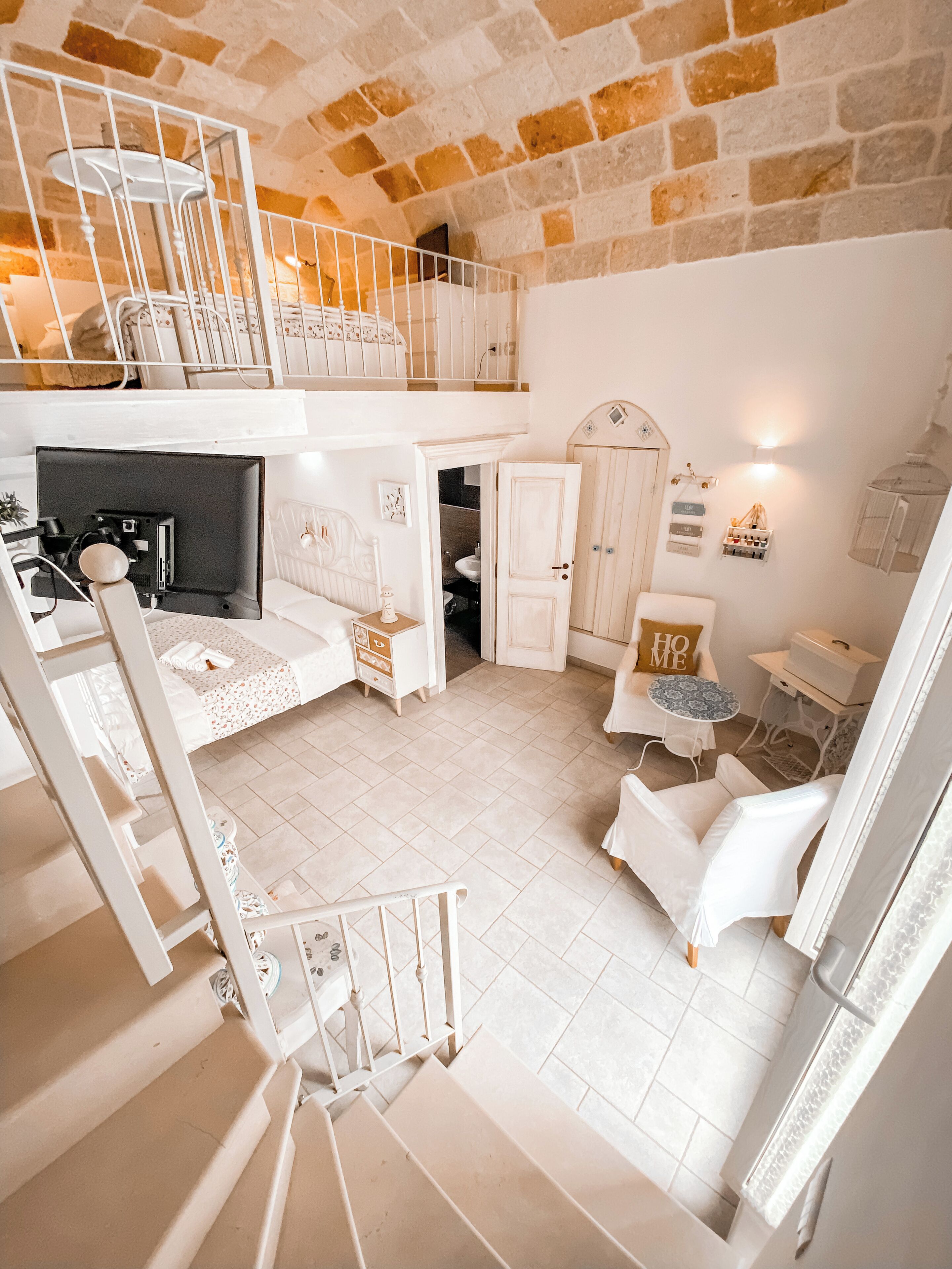 Un amplio espacio tipo loft con techo alto, paredes de ladrillo visto y una escalera que lleva a un nivel superior.